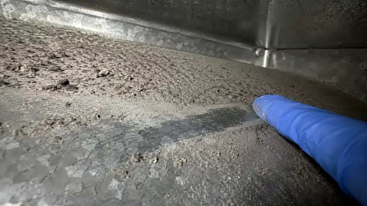 Primo piano di accumulo di polvere e particolato su una superficie metallica di una condotta di ventilazione