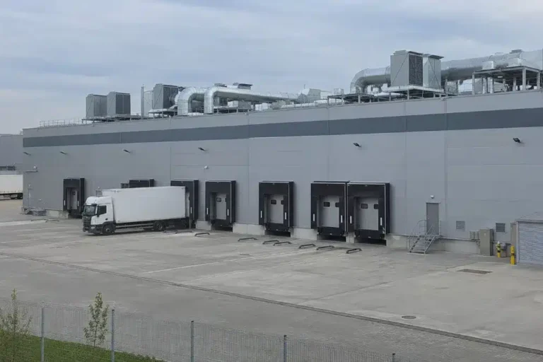 capannone industriale con piazzale di carico e unità di trattamento aria sul tetto, tipico sito con impianti aeraulici da manutenere