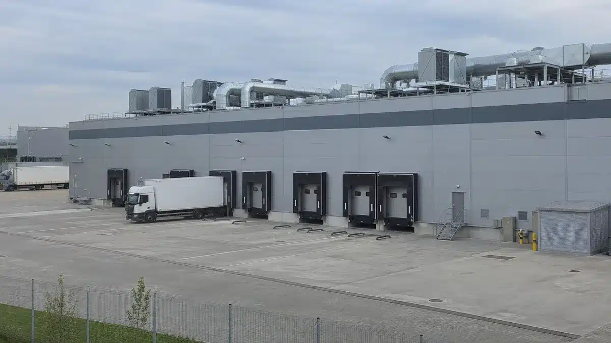 Capannone industriale con piazzale di carico, banchine e camion per il trasporto merci