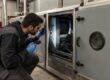 tecnico con tuta da lavoro e torcia ispeziona la sezione interna di una unità di trattamento aria con il pannello di ispezione aperto