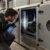 tecnico con tuta da lavoro e torcia ispeziona la sezione interna di una unità di trattamento aria con il pannello di ispezione aperto