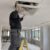 tecnico su scala smonta un diffusore a soffitto coperto di polvere di cartongesso per la pulizia delle condotte dopo una ristrutturazione