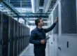 Tecnico controlla un'unità di trattamento aria in un data center vicino a rack server durante un intervento di manutenzione delle condotte