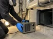 tecnico con semimaschera posiziona un generatore di ozono portatile davanti a una bocchetta di ventilazione per il trattamento ozono delle condotte aerauliche